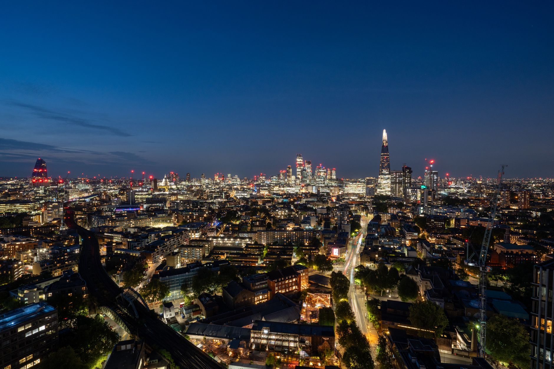 A wide shot of the London skyline at dusk, with modern buildings and a blurred digital interface overlay.