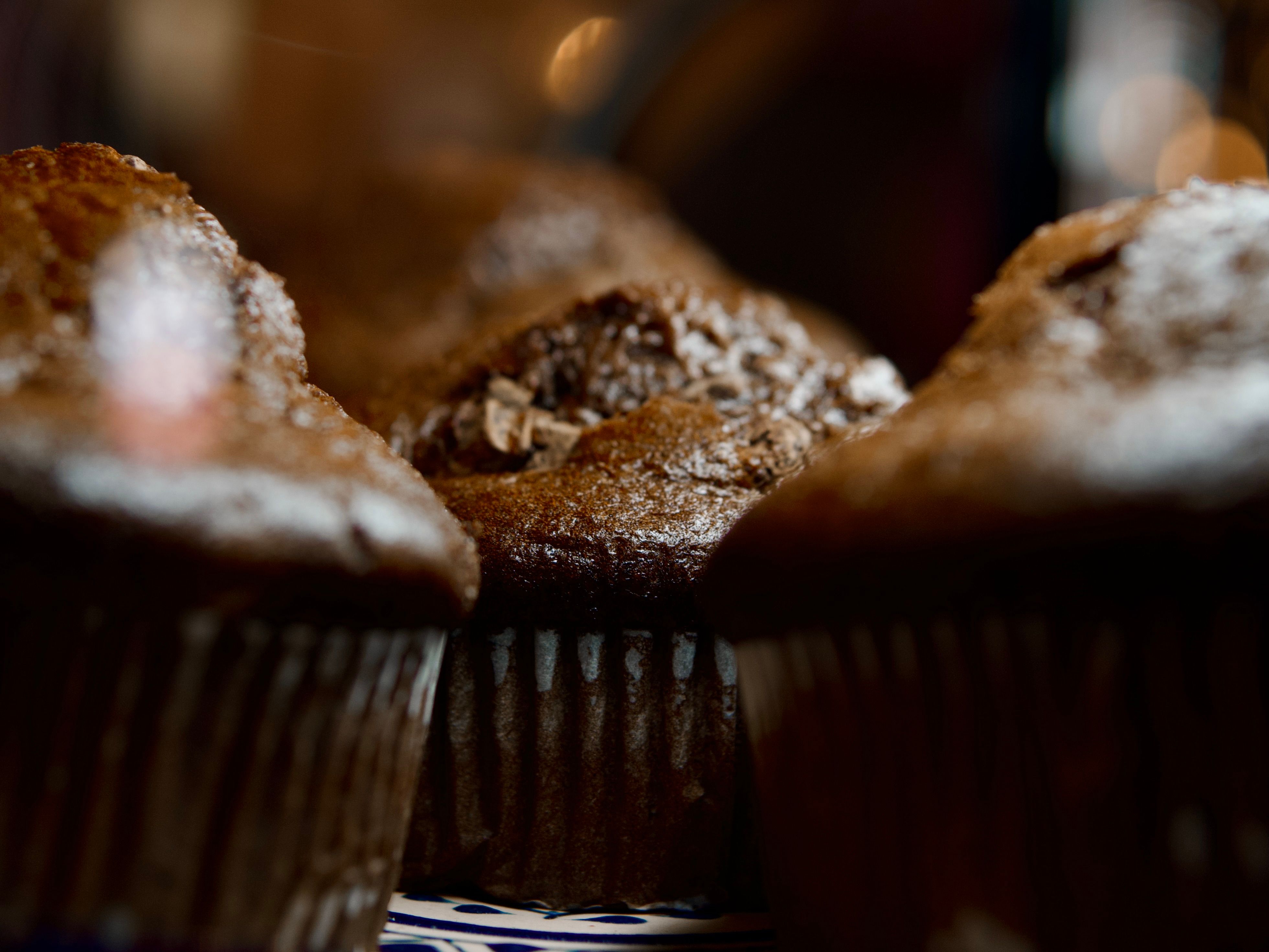 Delicious chocolate muffins captured in cozy ambient lighting, evoking sweet indulgence.
