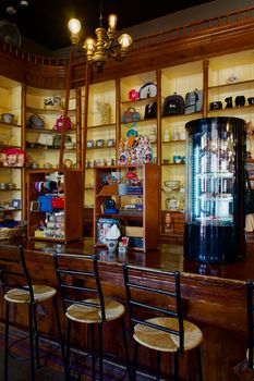 Warm and inviting café with wooden bar, stools, and shelves displaying various items.