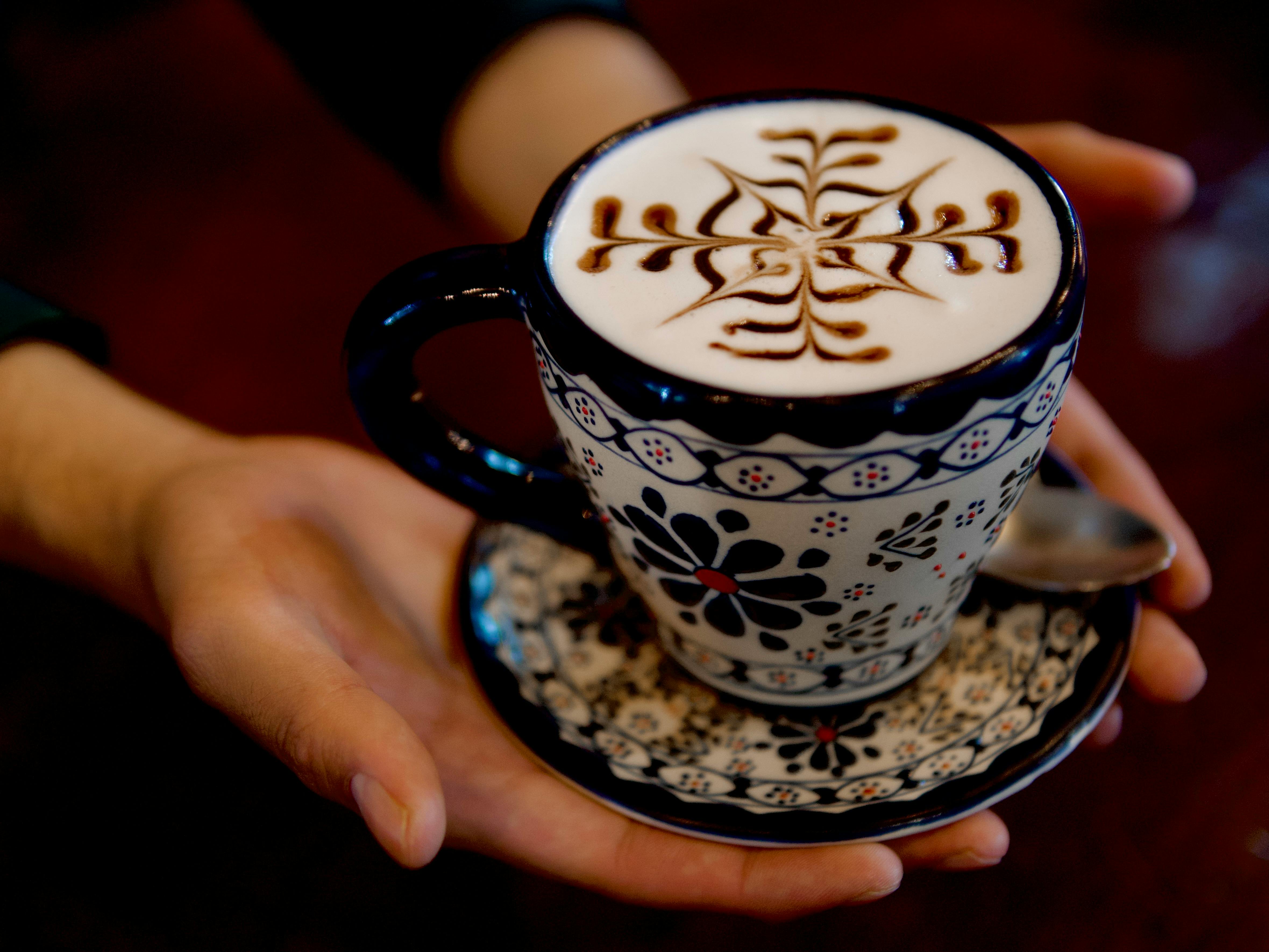 a person holding a cup of coffee with a design on it