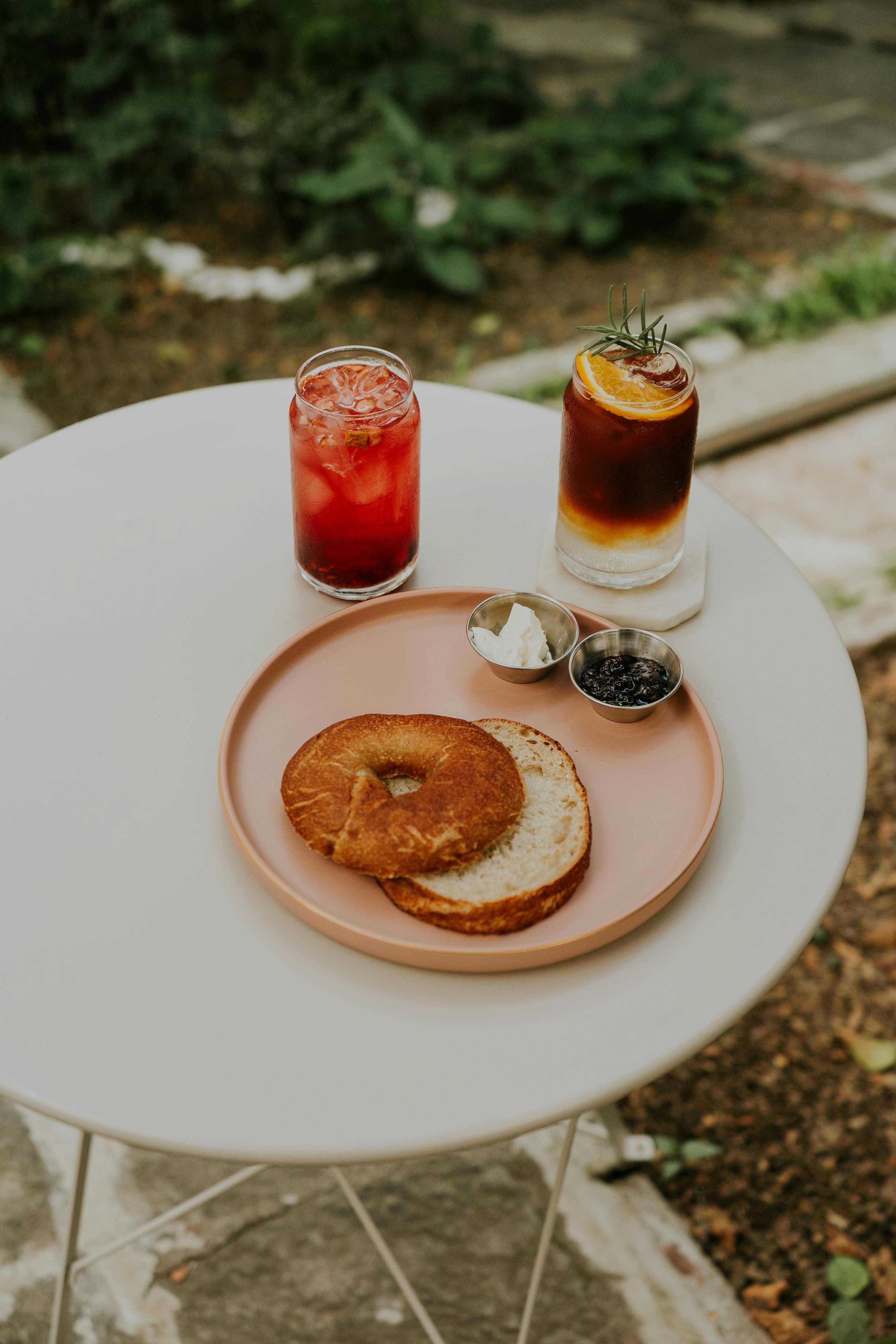 a pink plate with a bagel and a drink