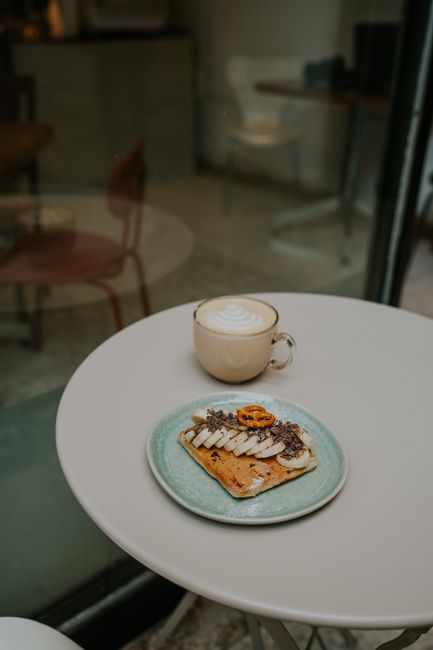 Inviting café scene with a cappuccino and toast topped with banana and chocolate.