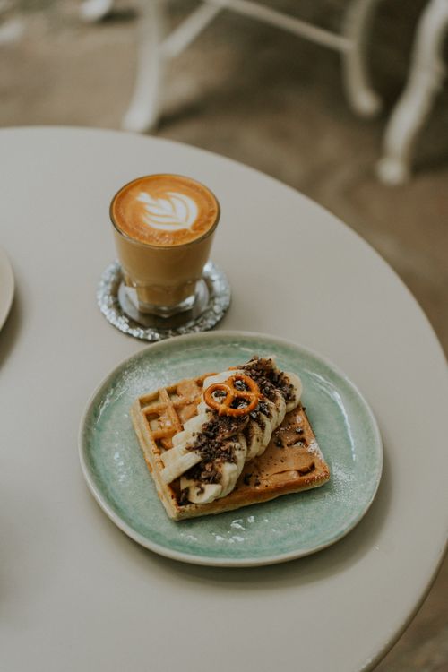 Free Indulge in a beautiful waffle with whipped cream and coffee at a cozy café. Stock Photo