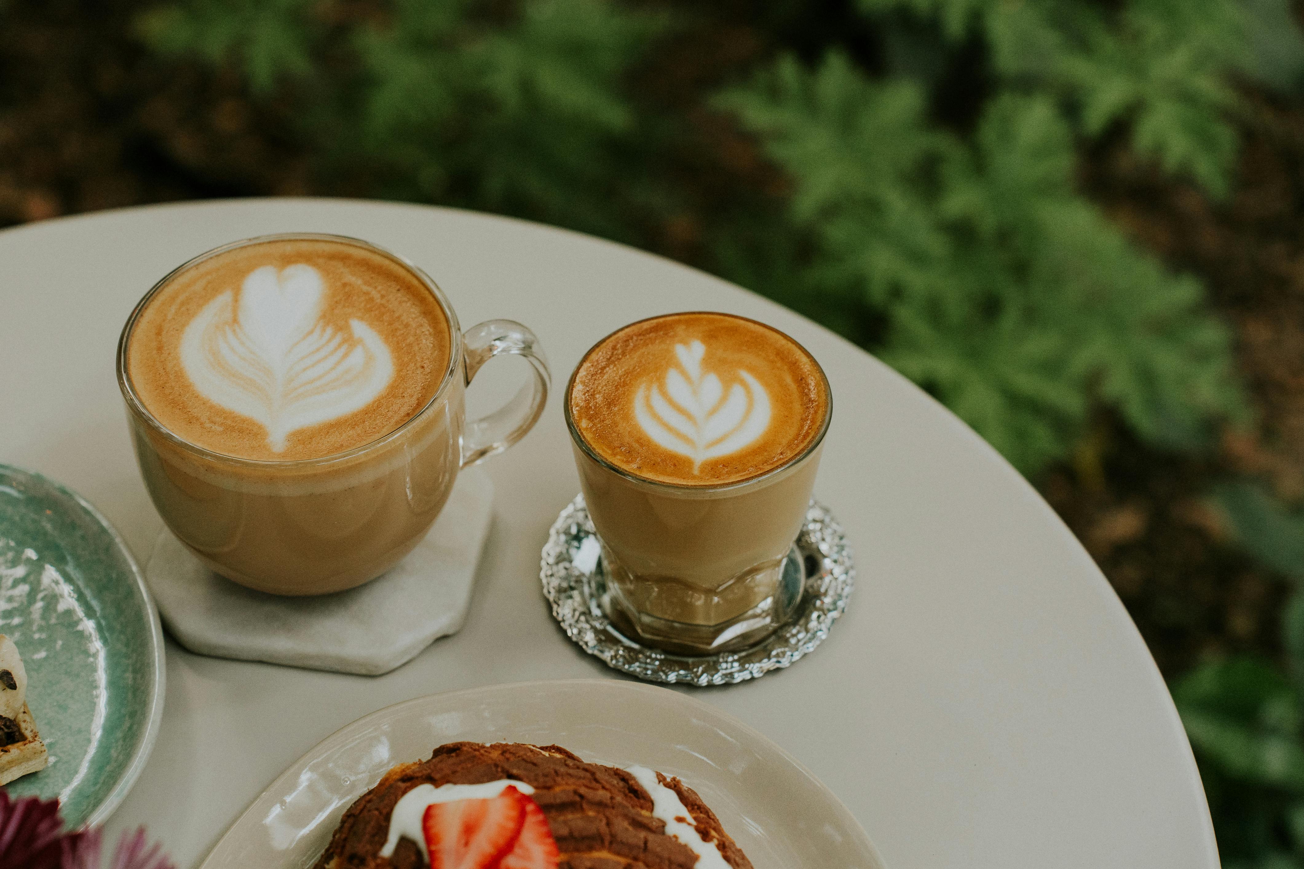 a table with two cups of coffee and a pastry