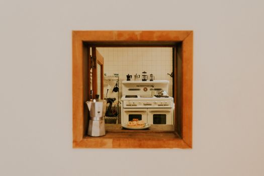 A warm, nostalgic view of a vintage kitchen captured through a wooden window frame, featuring a stove and coffee pot.