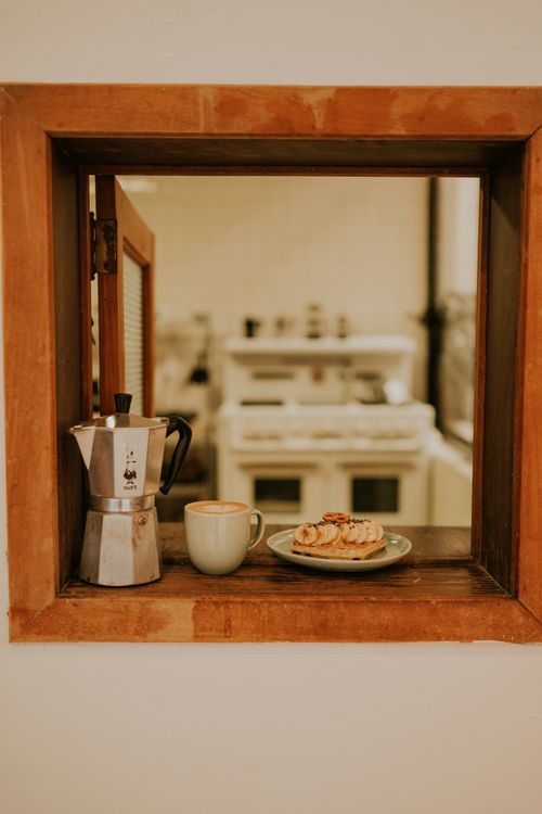 Free Rustic kitchen view with a coffee maker, mug, and pastries on a wooden ledge. Stock Photo