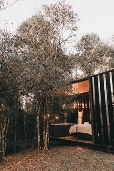 A cozy modern cabin with large glass windows nestled in a serene forest landscape, ideal for a peaceful getaway.