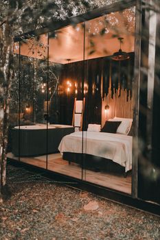 Luxurious glass-walled bedroom with modern decor surrounded by nature.