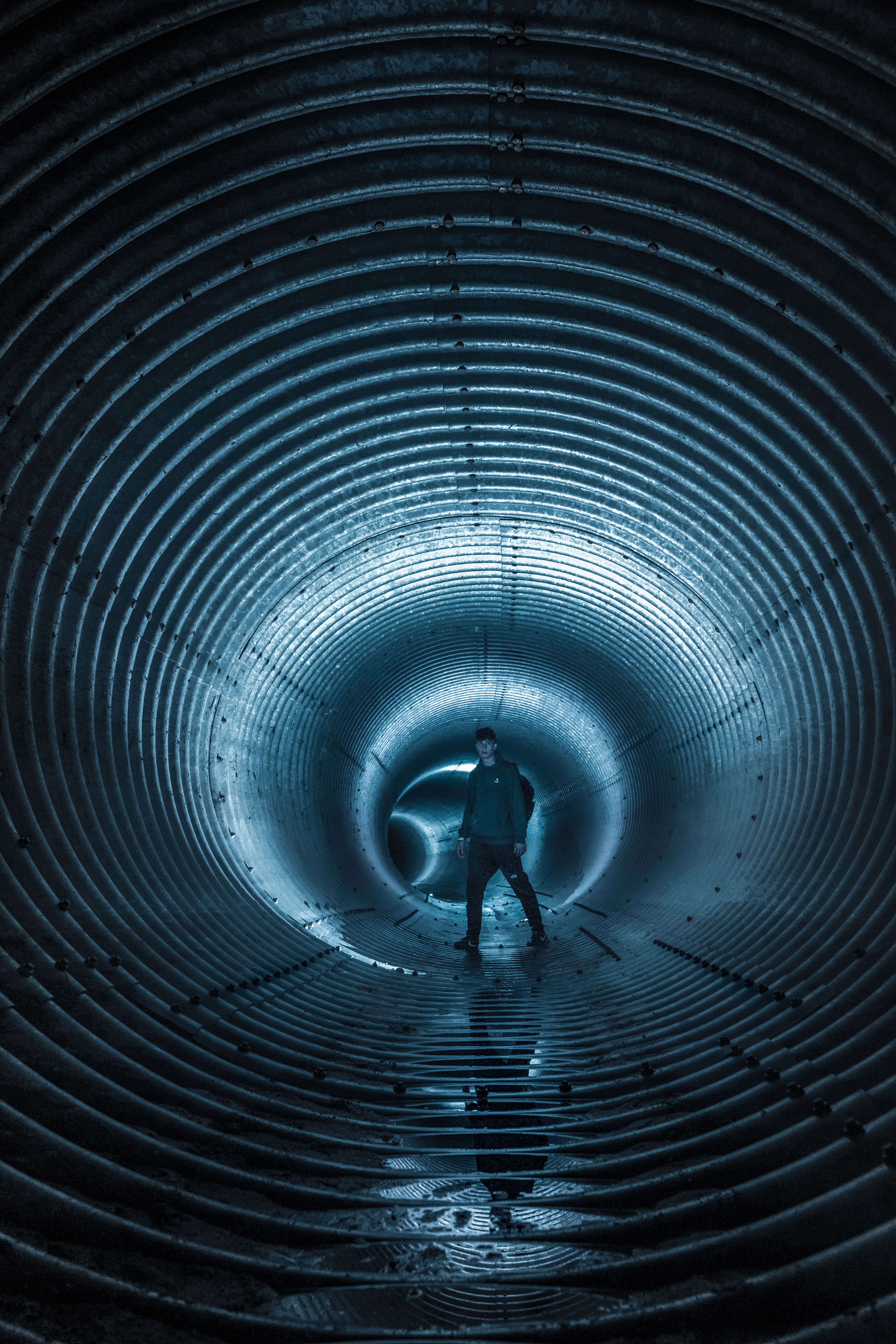 A man walking through a tunnel with a blue light · Free Stock Photo