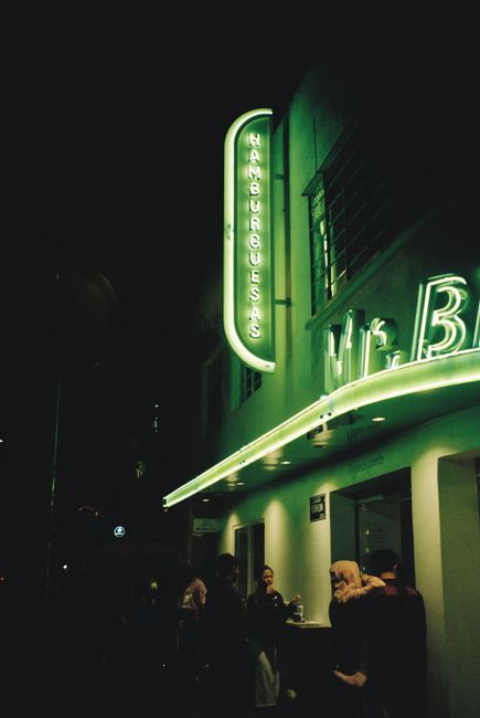 Vivid neon lights illuminate a bustling street in Mexico City at night, capturing the lively atmosphere.
