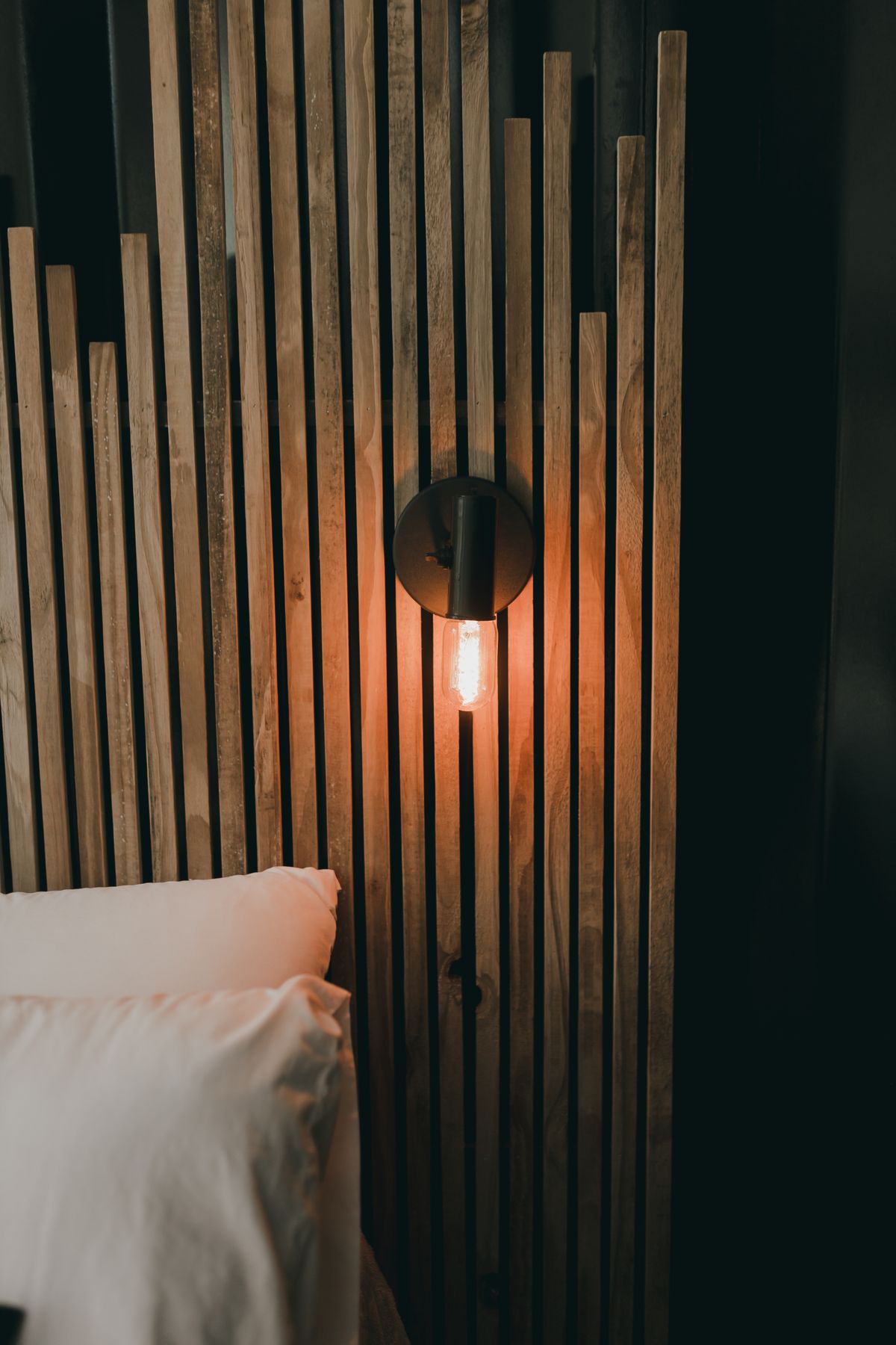 Warm LED strip glowing between vertical wood slats on a living room wall