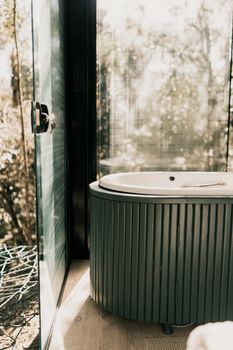 Stylish circular bathtub in a glass-walled bathroom with natural outdoor views.