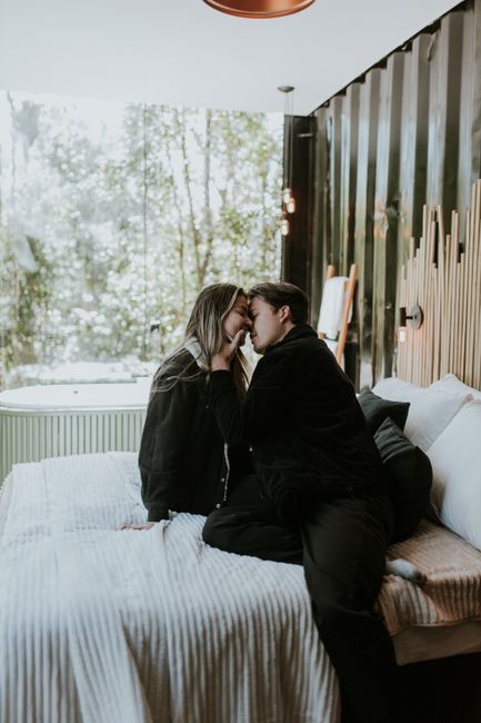 A loving couple embraces in a stylishly decorated bedroom with natural light.