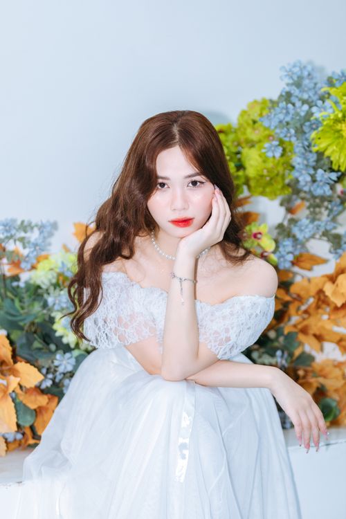 Free Beautiful woman in a white dress surrounded by colorful flowers, exuding elegance and grace. Stock Photo
