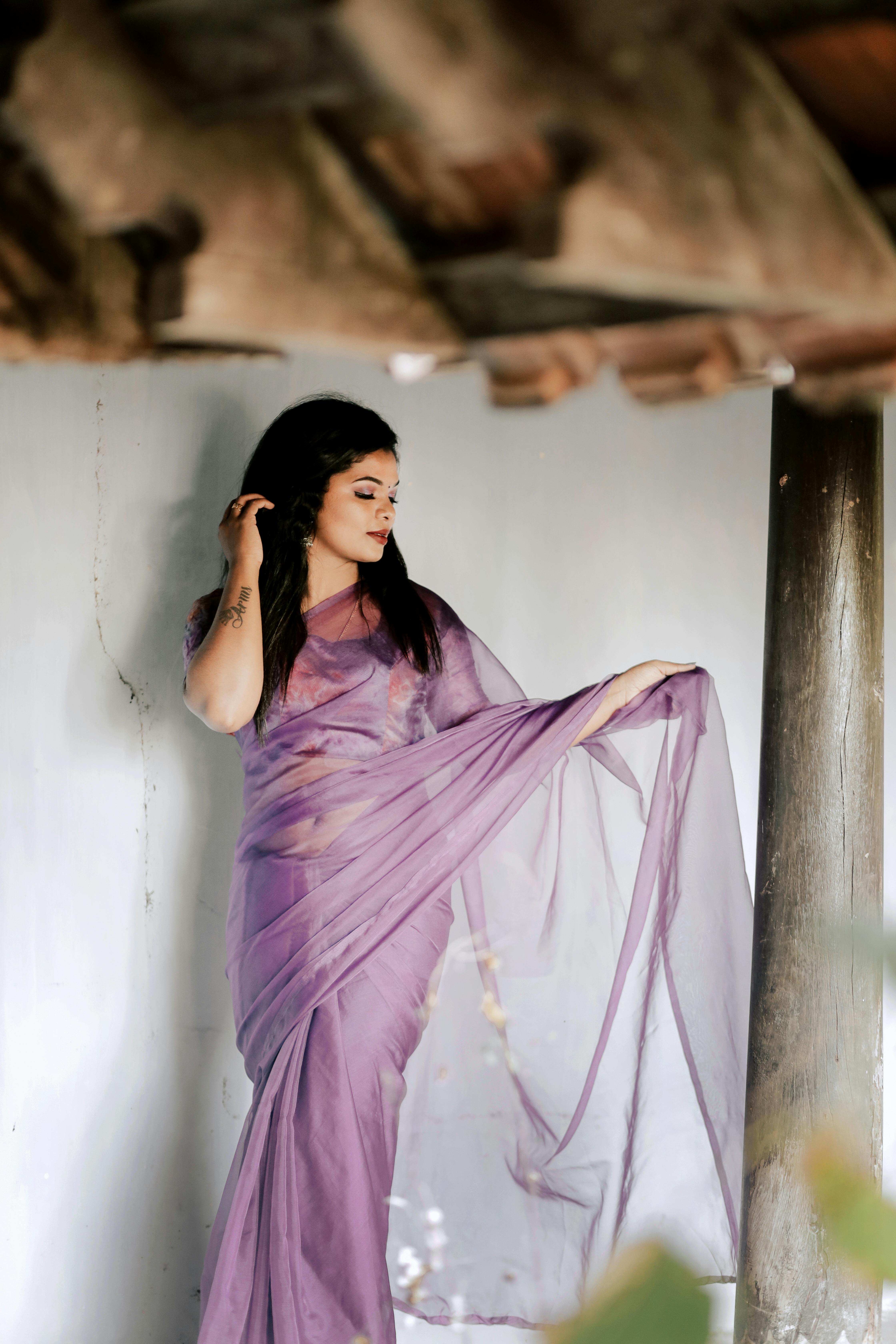 a woman in a purple sari leaning against a wall