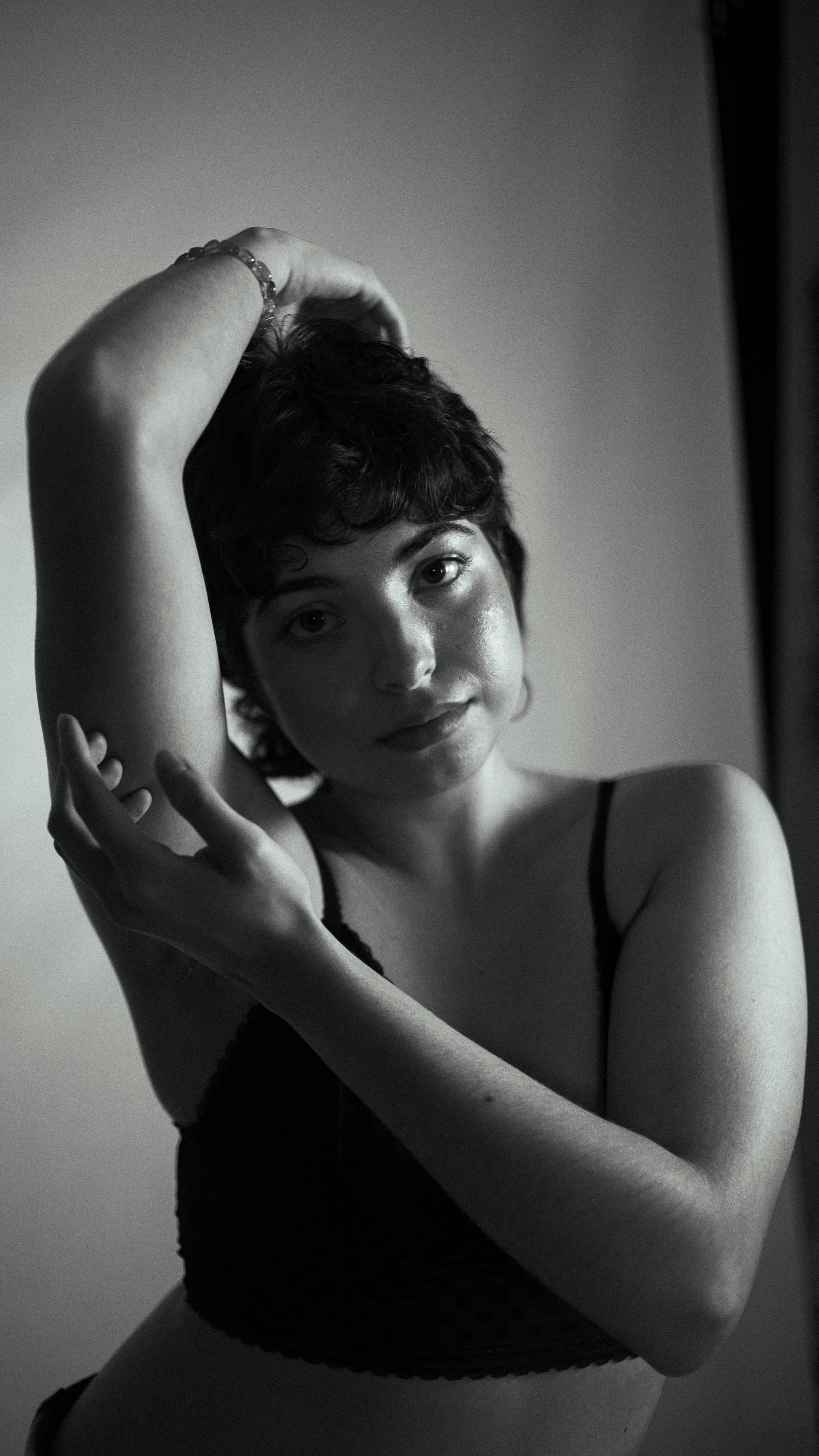 Monochromatic studio portrait of a pensive woman striking a graceful pose.