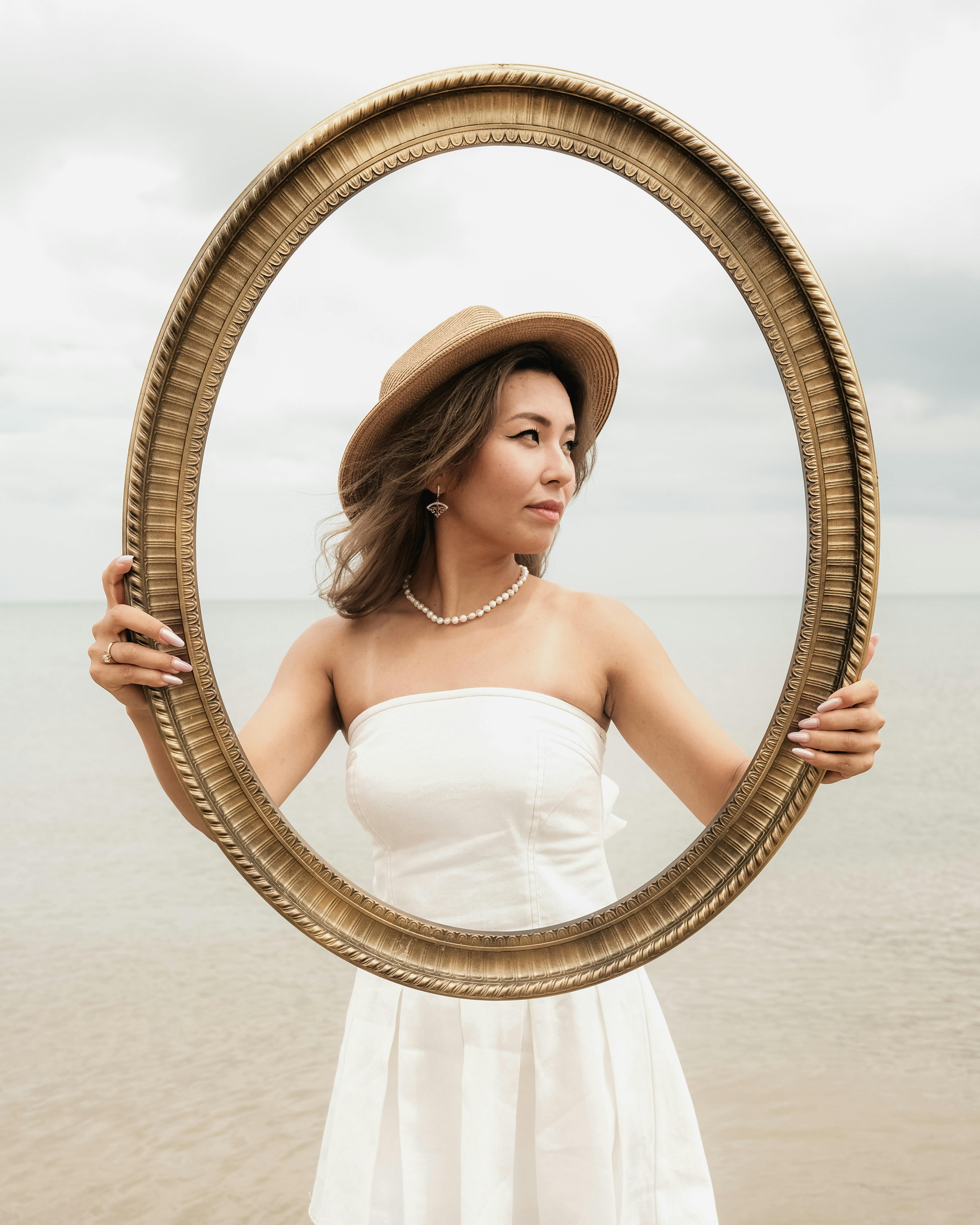 在宁静的海滩上，一名女子身穿白色连衣裙，戴着帽子，摆姿势