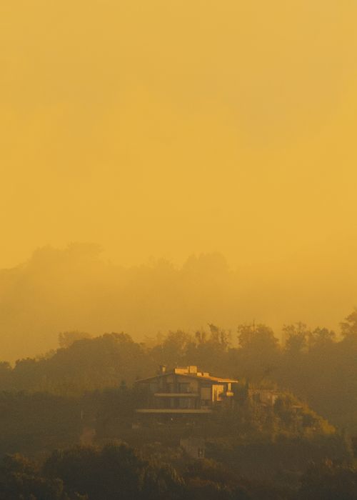 Free Serene sunset over misty forest with silhouetted chalet, creating a warm atmospheric landscape. Stock Photo