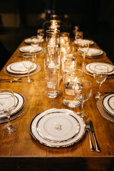 Luxurious table set for a candlelit dinner, featuring elegant tableware and glowing candles.