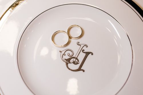 Free Elegant pair of wedding rings resting on a monogrammed porcelain plate, symbolizing unity and love. Stock Photo