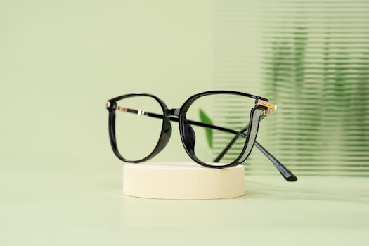 Modern black eyeglasses with a classic design resting on a minimalist display stand.