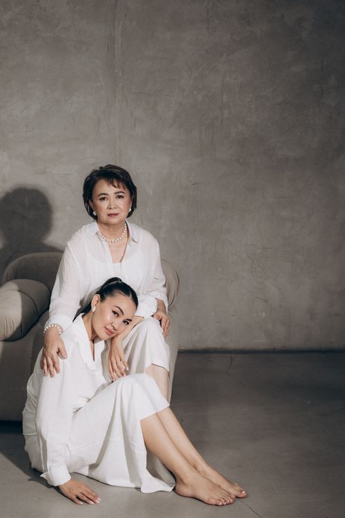 Free Elegant portrait of a mother and daughter sitting together indoors wearing white clothing. Stock Photo