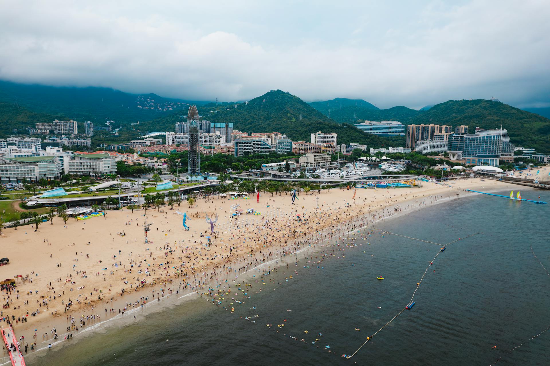 Scenic aerial view of a bustling beach in Shenzhen with mountains in the backdrop.