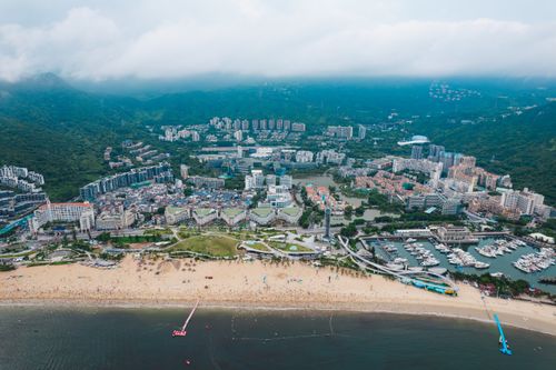 Free Stunning aerial view of Shenzhen's coastline, showcasing city, beach, and marina. Stock Photo