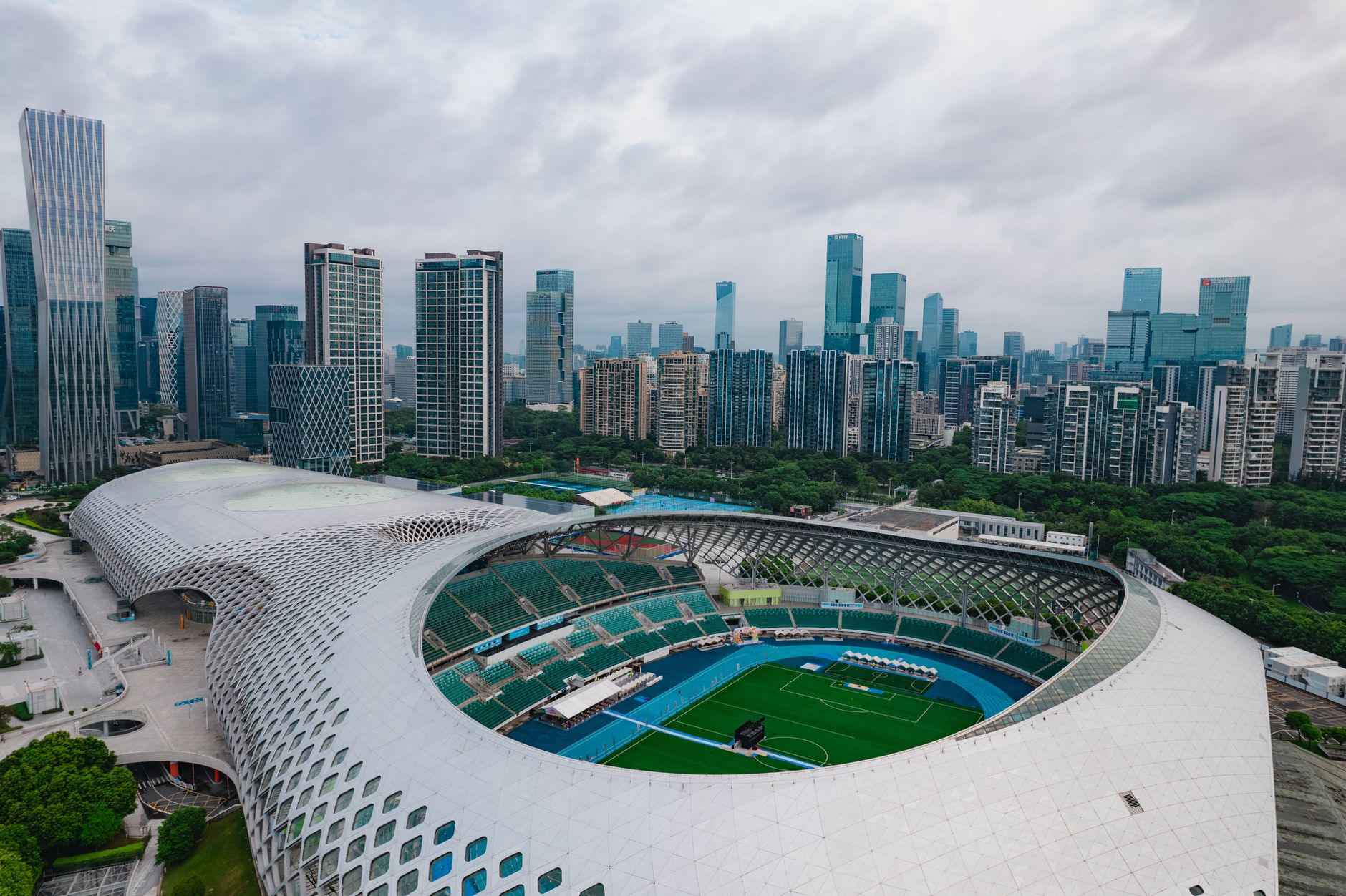 Stunning aerial shot of Shenzhen's modern stadium surrounded by skyscrapers, showcasing urban architecture and cityscape.
