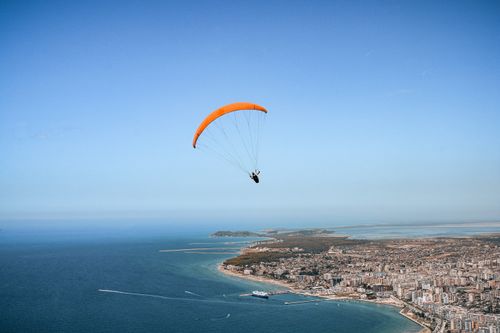 Free A thrilling paragliding experience over a beautiful coastal city with a vast ocean view. Stock Photo