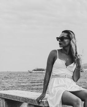 A stylish woman in sunglasses enjoying a seaside view, exuding elegance and leisure.
