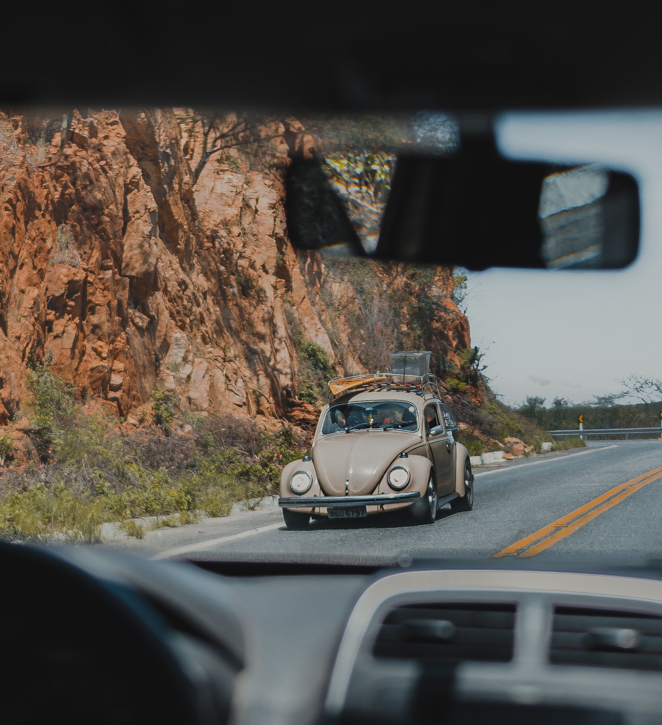 A vw beetle driving down a road with a mountain in the background ...