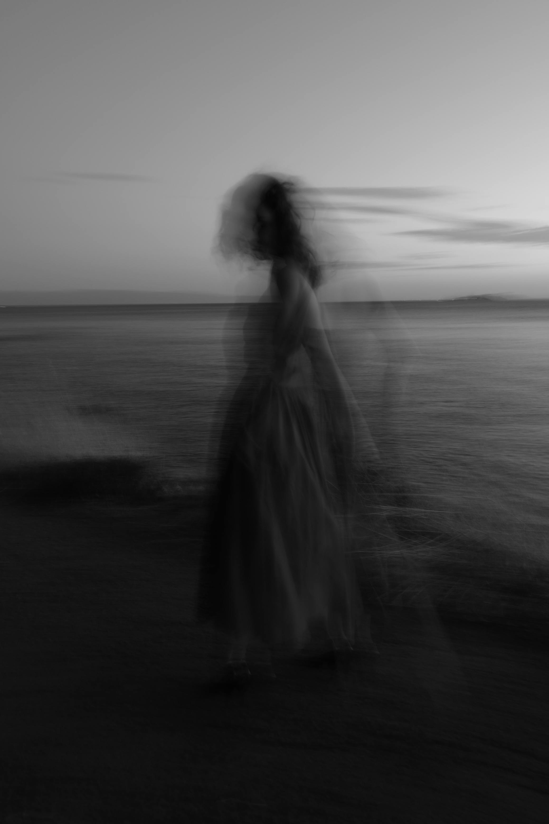 Blurred silhouette of a woman in a long exposure photo on Kınalıada Beach at dusk.