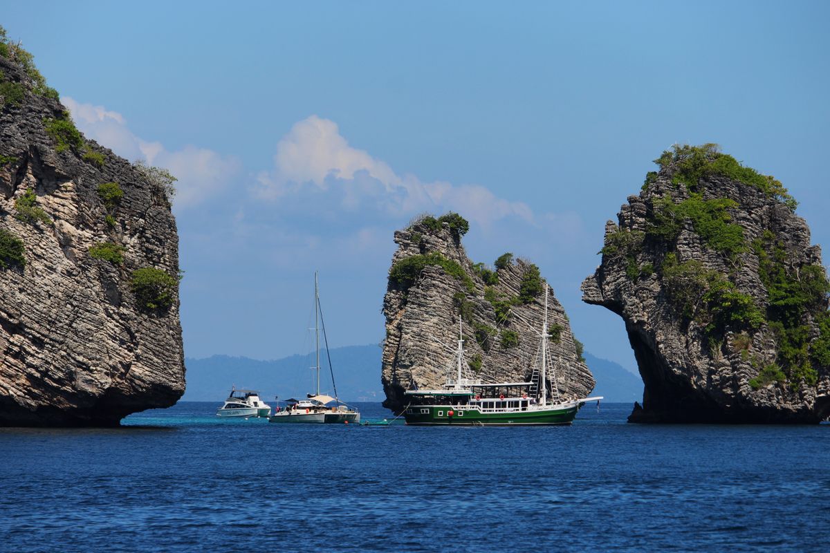An Offshore Rock Formation Surrounded By Speedboats · Free Stock Photo