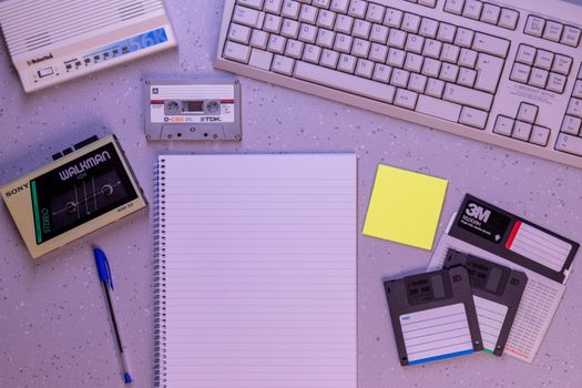 An arrangement of retro office supplies featuring vintage electronics and media on a desk.