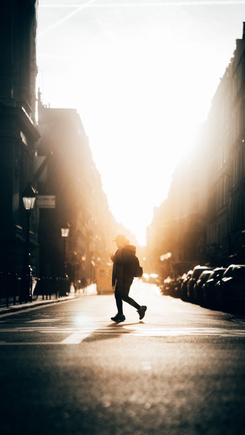 Free Captivating silhouette of a person walking across a Paris street during golden sunset hour. Stock Photo