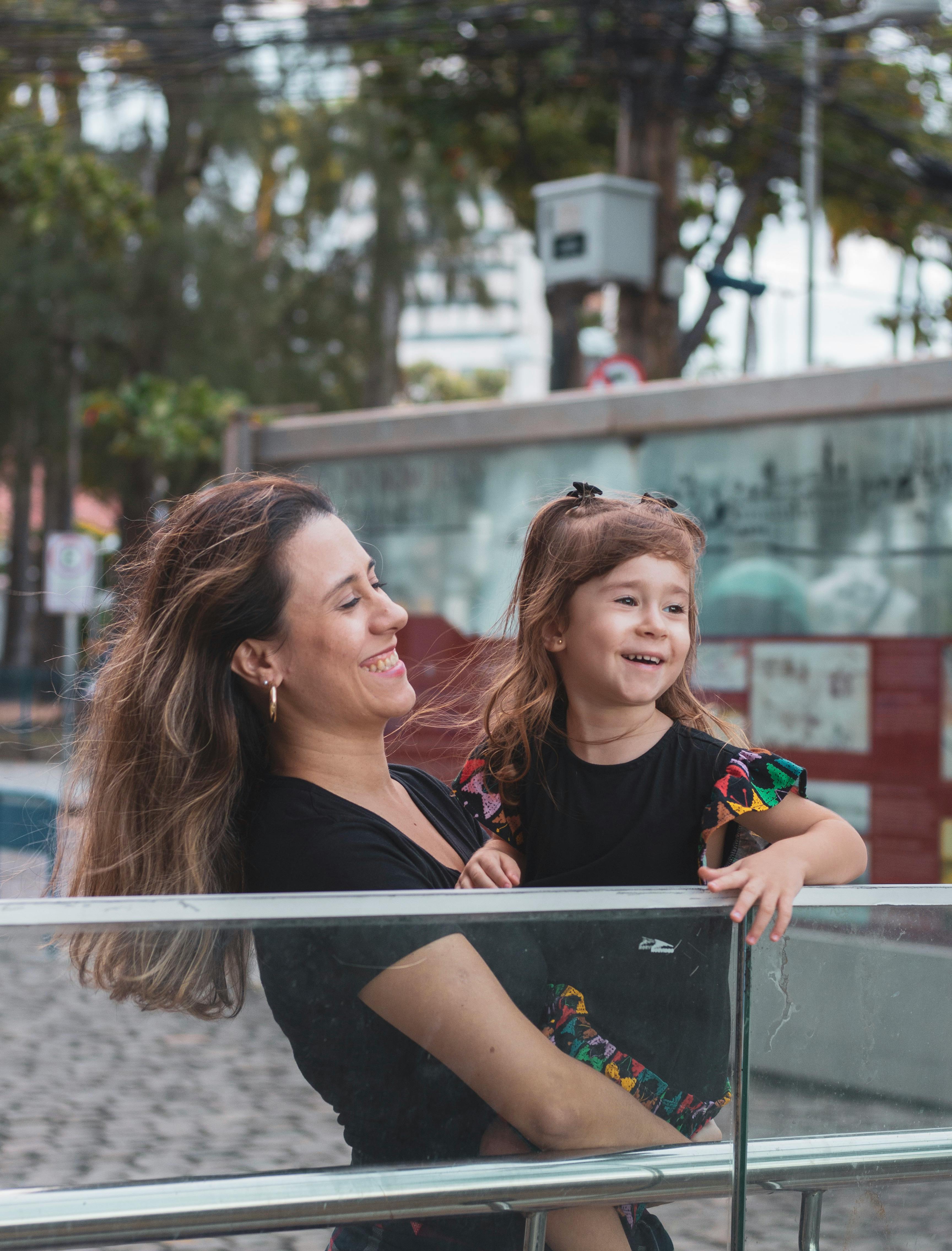 a woman and child are standing on a railing