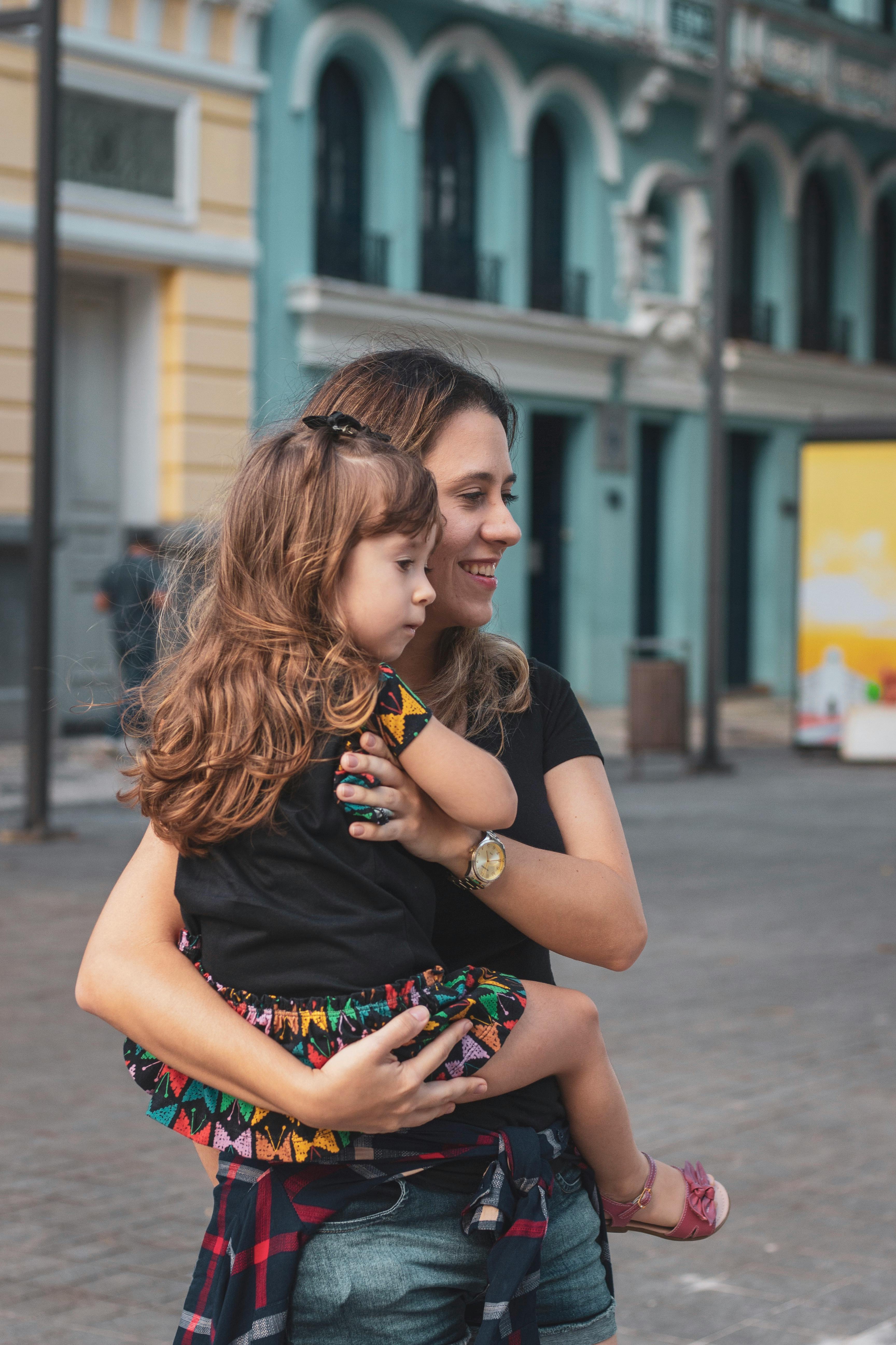 a woman holding a child in front of a city