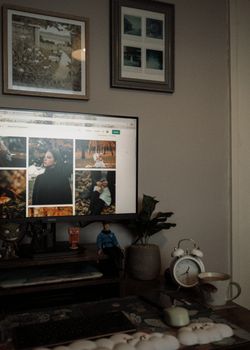 A comfortable home workspace featuring a monitor, decor, and wall art in a cozy setting.