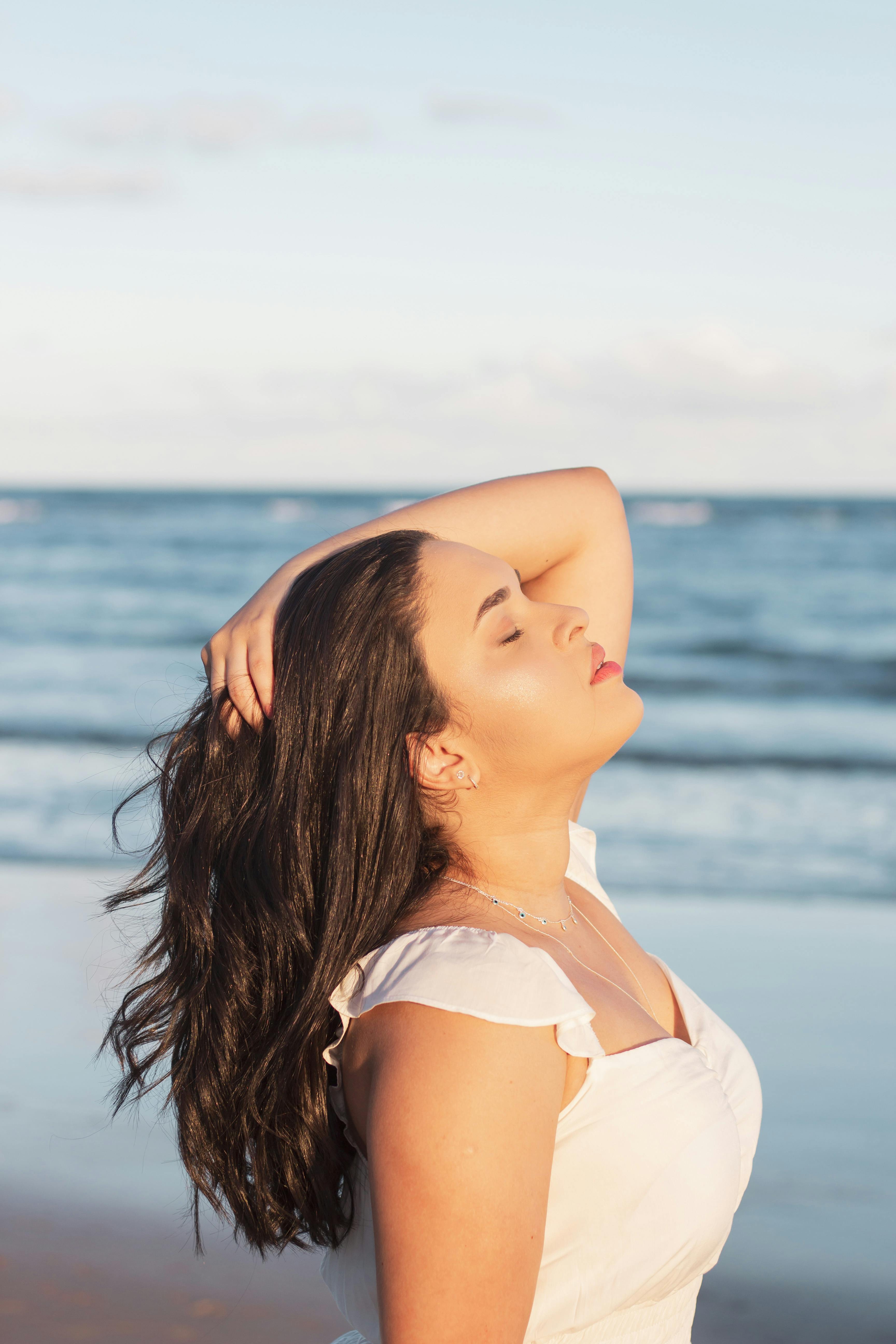 a woman in a white dress is standing on the beach