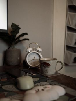 A cozy home office scene featuring a vintage clock and a nature-themed mug on a desk.