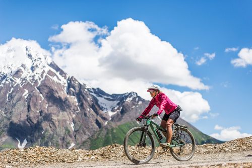 Free A cyclist rides through a mountainous trail on a sunny summer day, showcasing adventure and freedom. Stock Photo