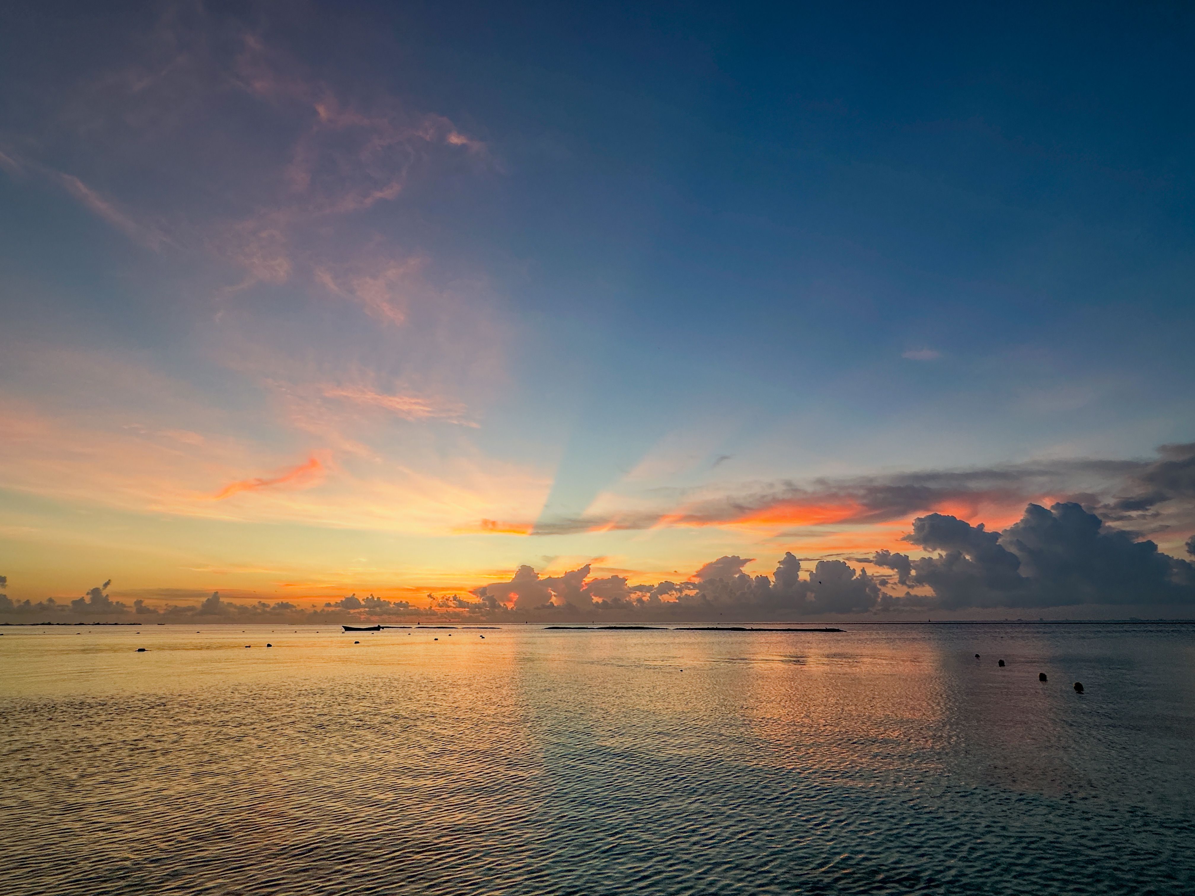 A sunset over the ocean with clouds and boats · Free Stock Photo