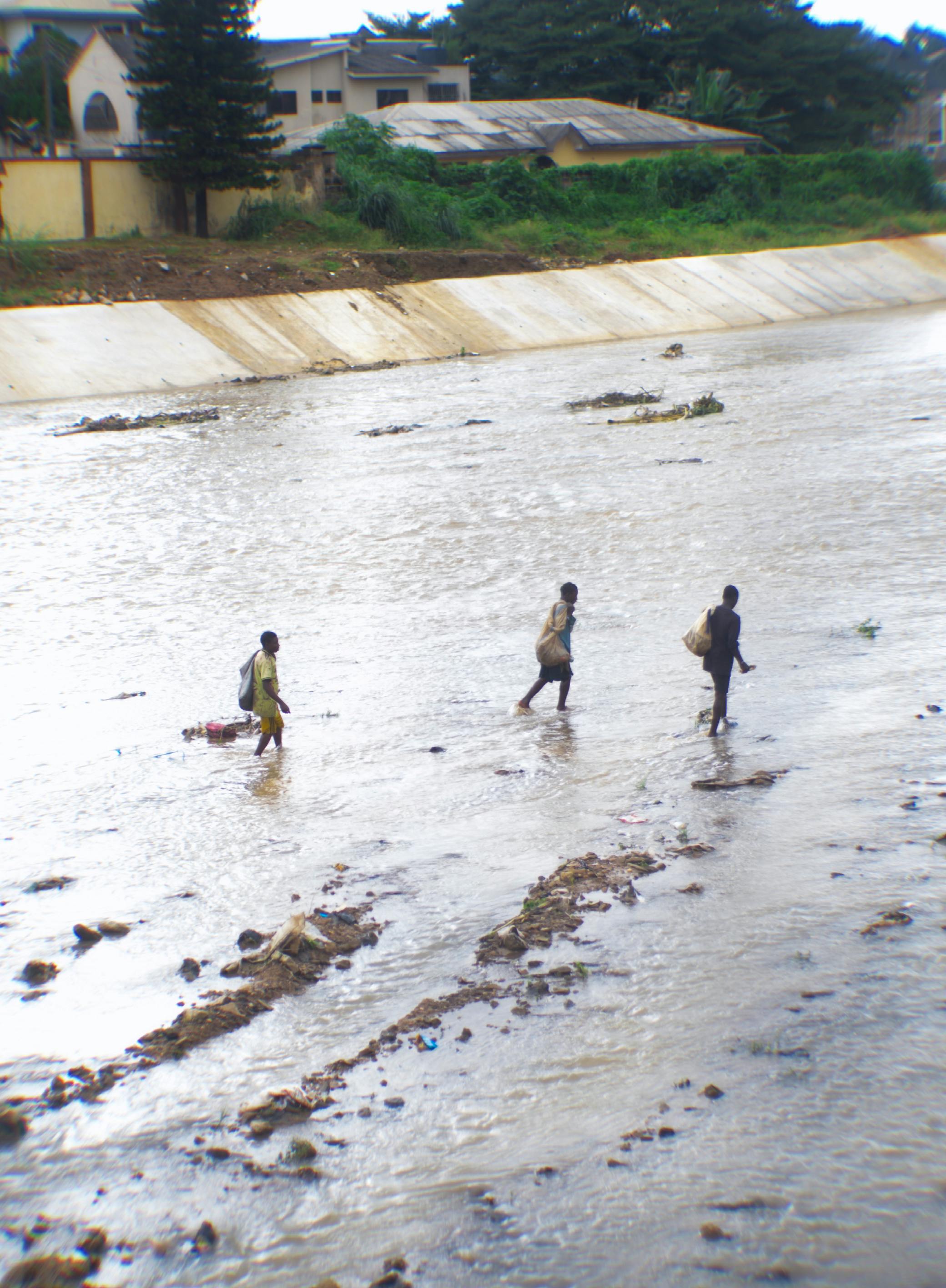 Three individuals navigate a flooded river, illustrating resilience amidst natural challenges.