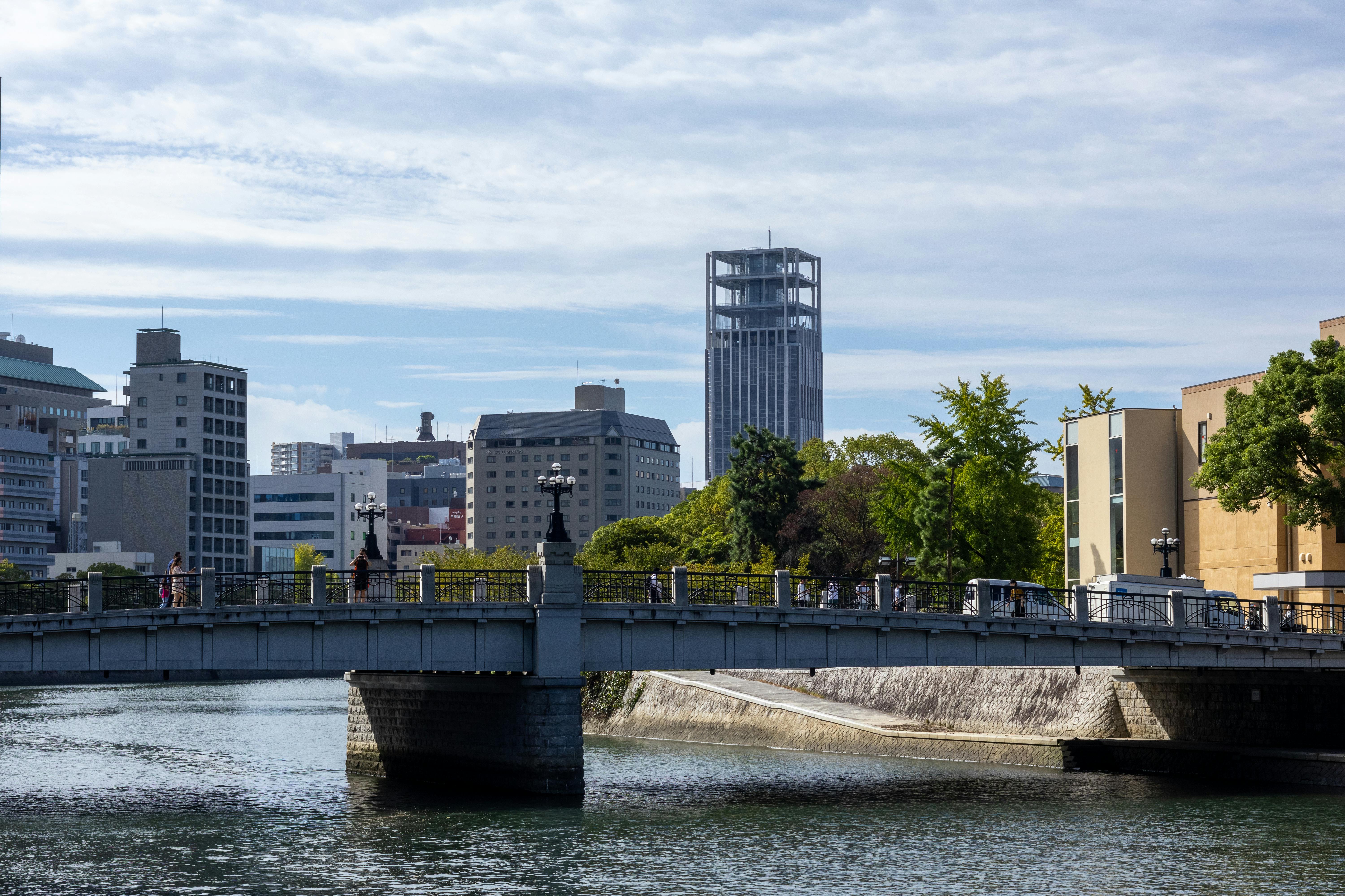 Scenic view of a bridge and skyline in Hiroshima, showcasing modern architecture under a clear sky.