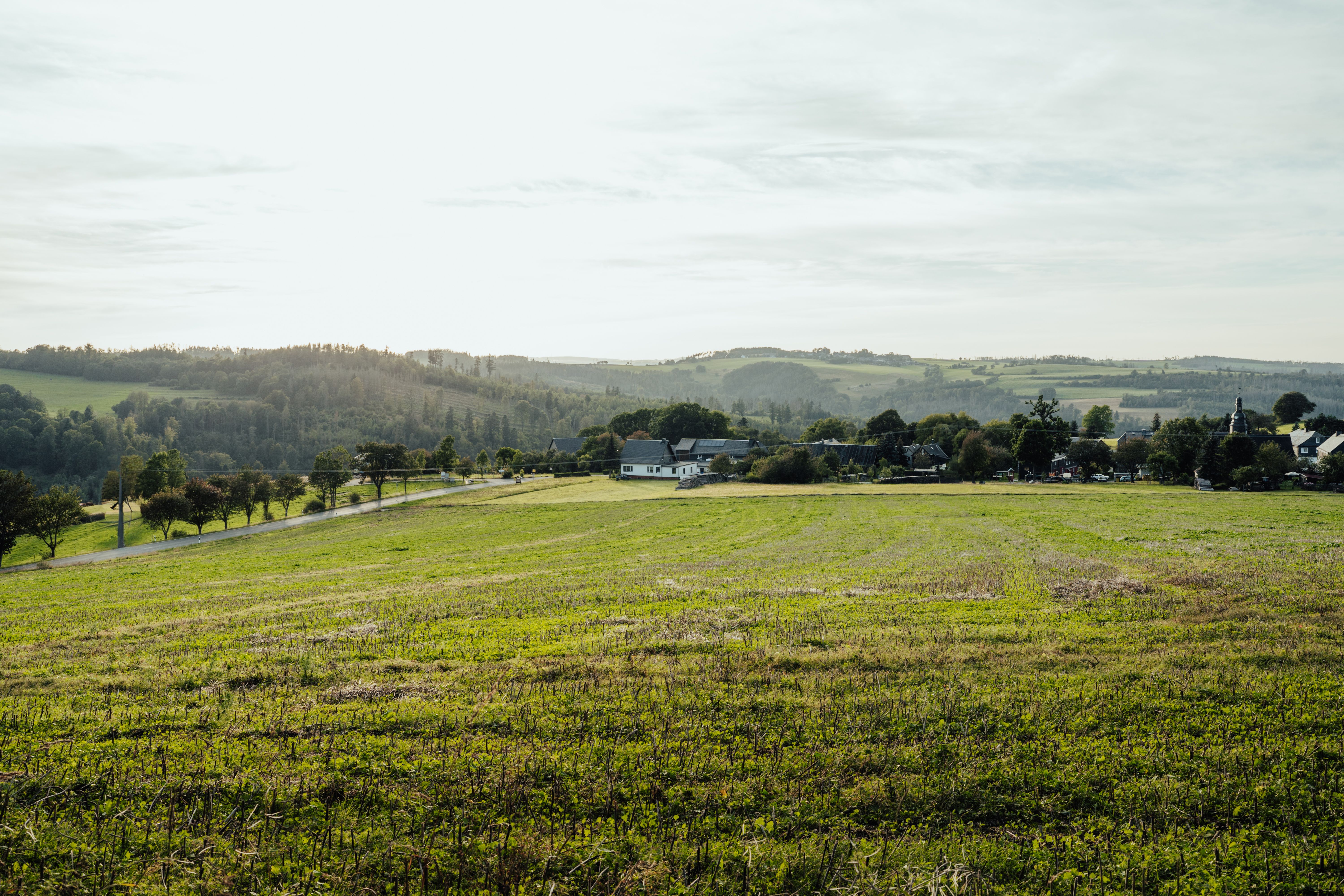 A field with a green grassy area and a house in the distance · Free ...
