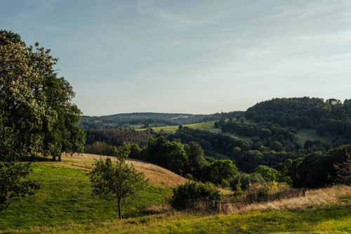 Free Explore the tranquility of rolling hills and lush greenery under a clear summer sky. Stock Photo