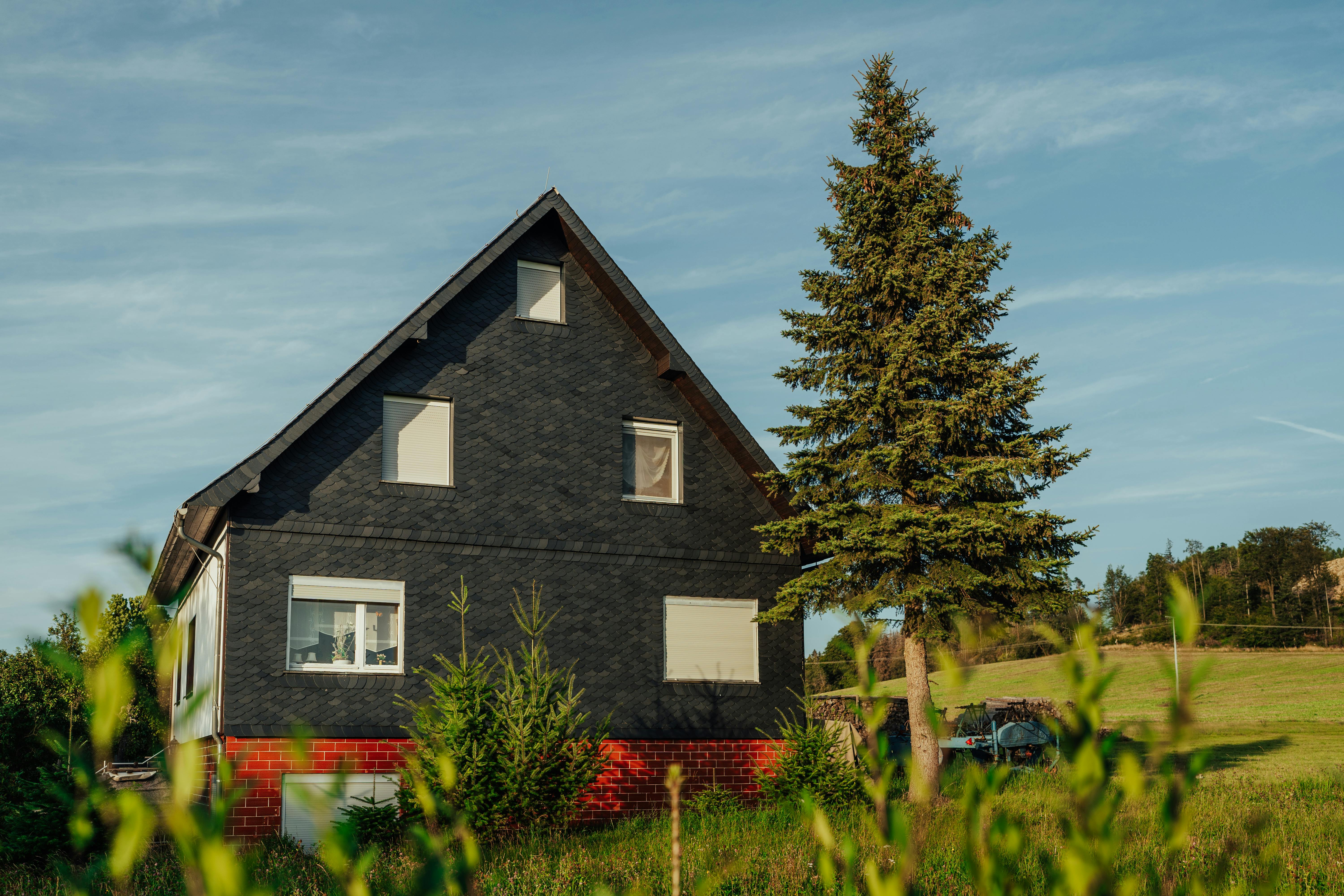 a black house with a tree in front of it