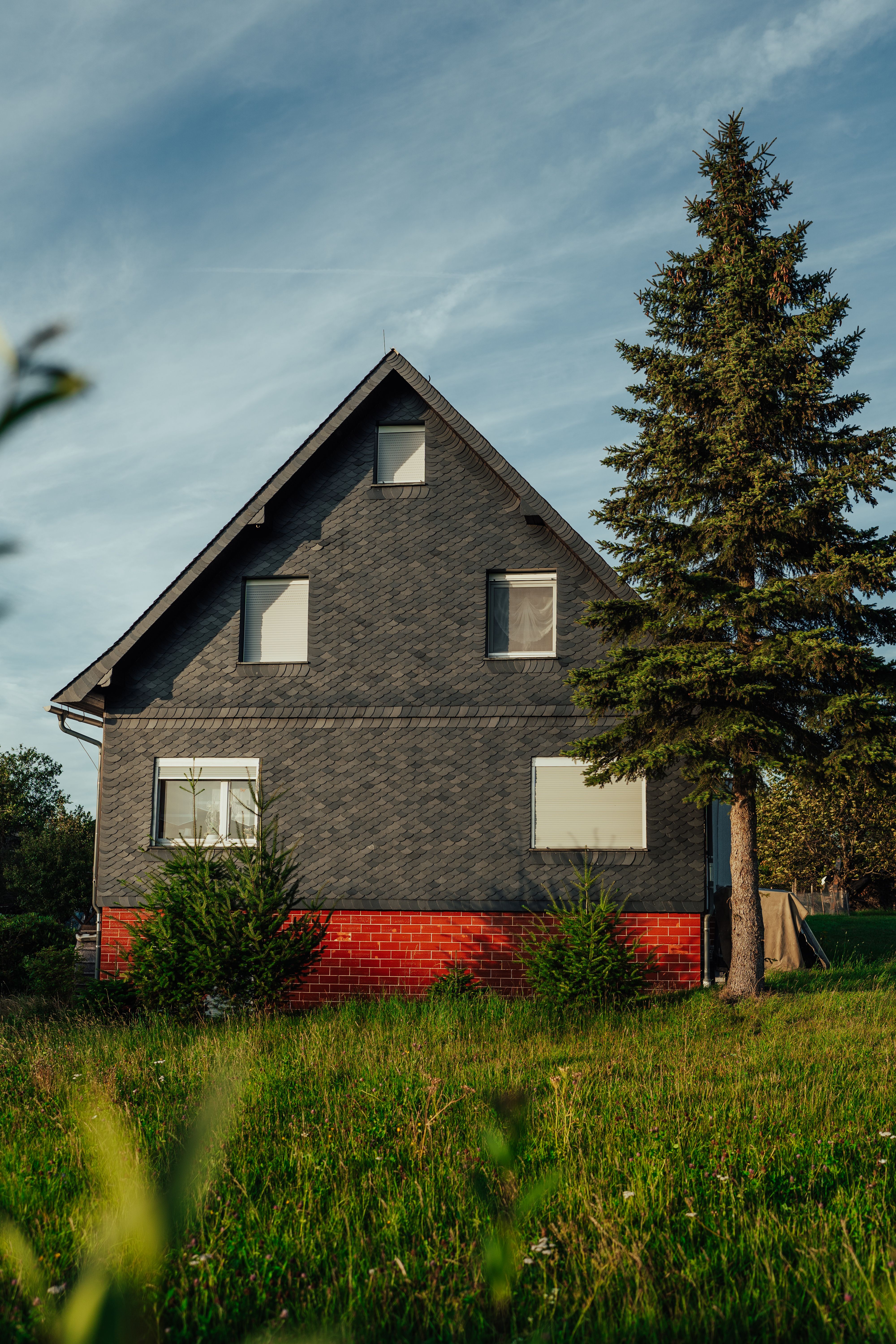 A picturesque rustic house surrounded by lush greenery under a clear summer sky.