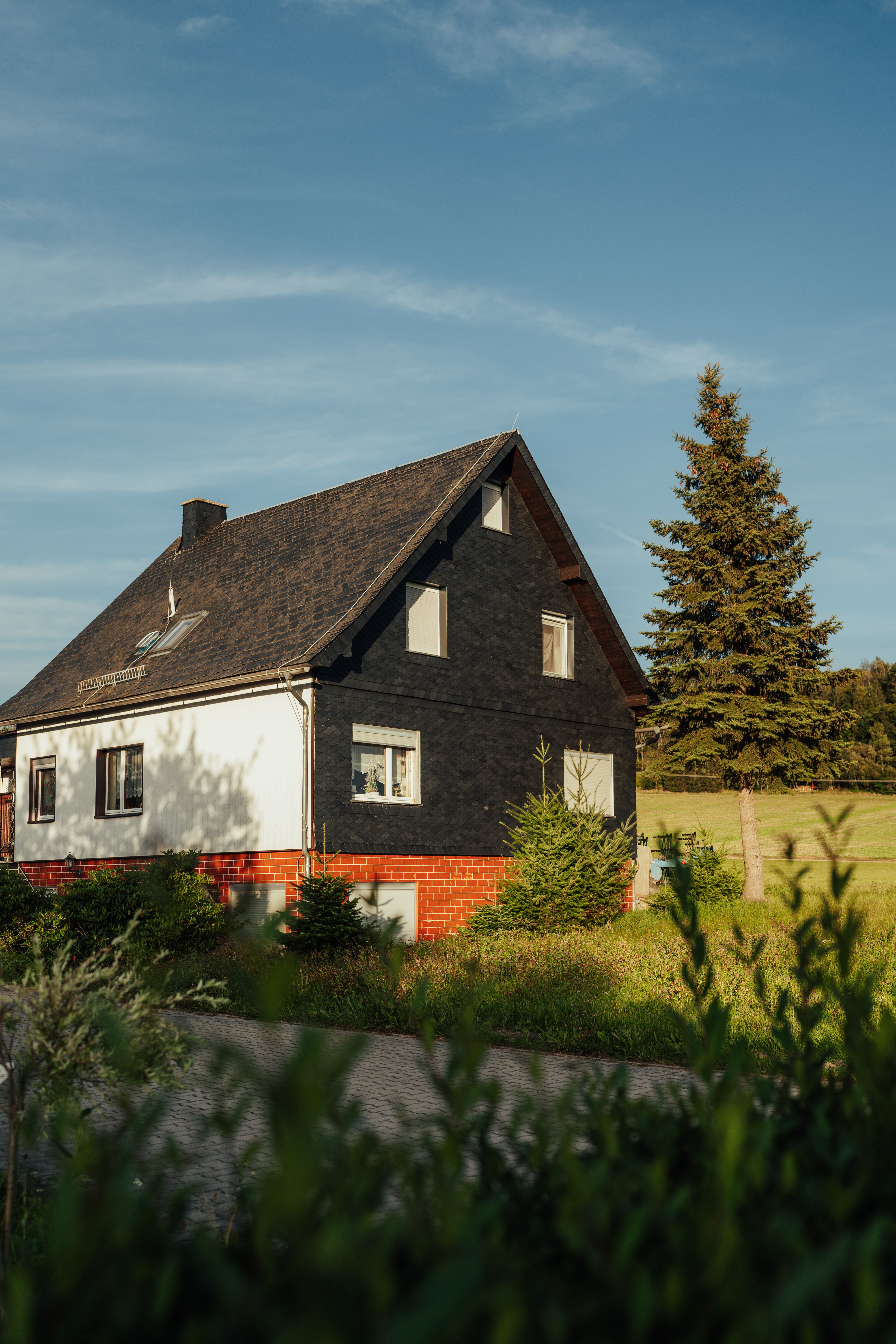 Cozy country house surrounded by greenery under a clear summer sky.
